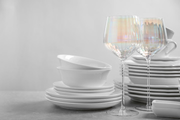 Set of clean dishes and glasses on light grey table