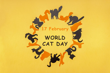 Happy International Cat Day in Europe. Round frame made of orange and black cat silhouettes on yellow pastel background. Festive layout for feline holiday, text FEBRUARY 17 WORLD CAT DAY. Flat lay