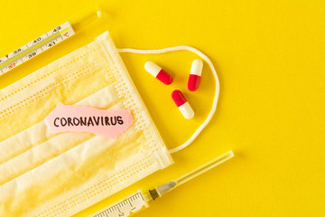 Coronavirus. 2019-nCoV. Protective medical mask, thermometer, syringe and the inscription coronavirus on a piece of paper on a yellow background. The concept of virus protection. Selective focus.
