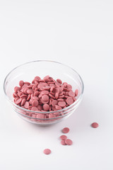 Ruby Chocolate Callets, in a transparent bowl, on white background.