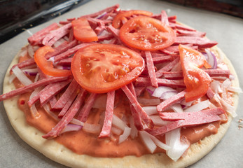 Pizza making process.	Pizza dough with raw ingredients, close up