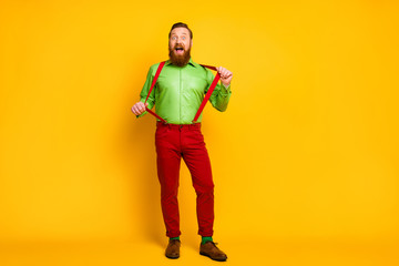 Full body photo of attractive funny guy model good mood playful macho wear green shirt red suspenders pants socks footwear isolated vibrant color background