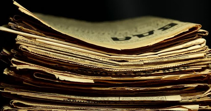 Stop motion a stack of old yellowed newspapers information transfer concept.