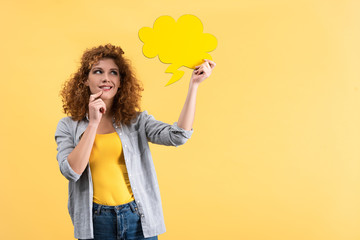 dreamy girl looking at empty speech bubble in shape of cloud, isolated on yellow