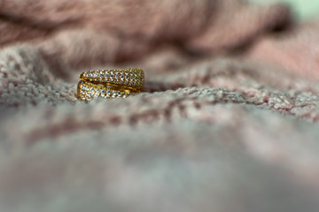 Gold modern earrings of large size, completely covered with small white transparent stones cubic Zirconia, creating artificial gold in a fashionable piece of jewelry on a velvet pink background