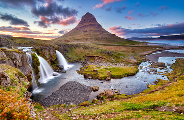 Colorful sunrise on Kirkjufellsfoss waterfall. Amazing morning scene near Kirkjufell volkano, Iceland, Europe. A famous tourist attraction near the city of Grundarfjordur. Travel concept background.