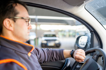 A man driving a car and looking on the watch