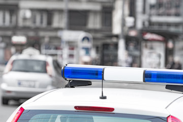 Police car with blue lights on the crime scene in traffic / urban environment.