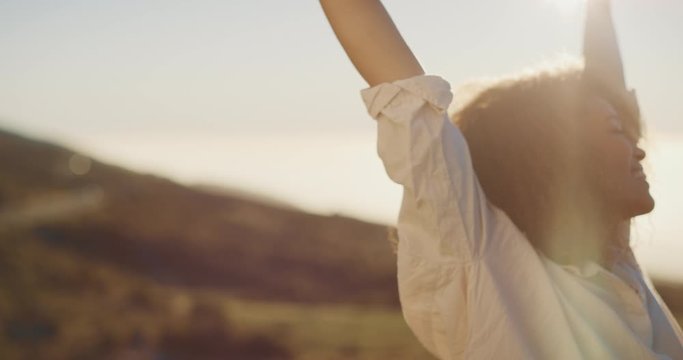 Happy african american woman raising her arms into the air and embracing the afternoon sun, woman expressing herself and feeling endless possibilities