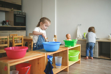 Toddler whips soap suds in basin at Montessori