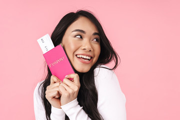 Image of happy brunette asian woman holding passport and travel tickets
