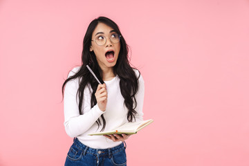 Image of young asian woman wearing eyeglasses making notes in diary book