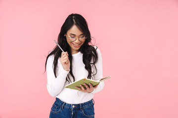 Image of young asian woman wearing eyeglasses making notes in diary book