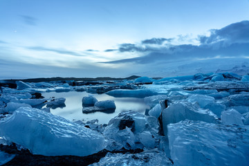 iceland glacier jokulsarlon in the evening icebergs floating on the cold peaceful water after sunset with dramatic sky .