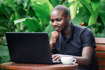 African man using a laptop computer outside a coffee cafe