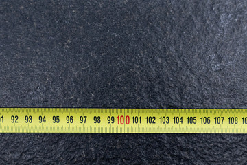 One meter on Yellow tape measure on black stone. Measurement tools for construction and carpentry,...