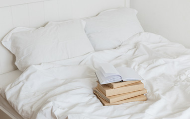 Fototapeta na wymiar Books on bed white bed linen.
