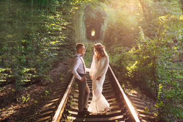 green tree tunnel and couple is standing on railway and look at