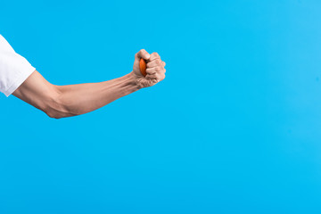 cropped view of angry man squeezing stress ball, isolated on blue