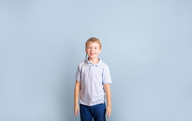 Fototapeta premium positive blond boy having fun on a blue background, the concept of a happy and joyful childhood