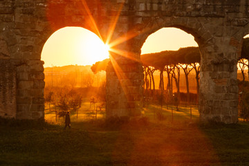 man walks at sunset, under the majestic arches of the Roman aqueduct