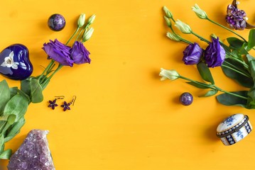 Purple flowers and women's accessories and jewelry on a yellow wooden background