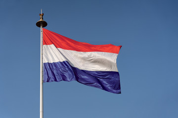 Waving Flag of Holland on a Flag Poll Against Blue Sky