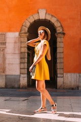 Fototapeta na wymiar A beautiful girl in a yellow dress poses in front of the arch of