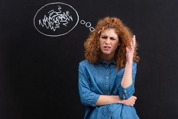 stressed redhead young woman with thought bubble on blackboard
