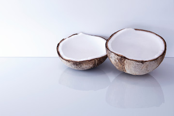 Fresh open coconut on white glass background with reflections.  Elegant fresh tropical coco with copy space.