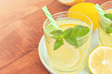 Lemon lemonade in mason jar glass ofwith lemons and straw on table background