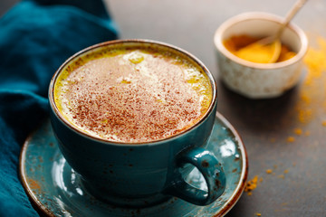Closeup view of turmeric latte cup on a textured dark background.