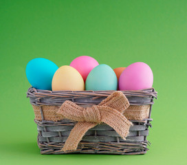 Happy easter, dyed colored eggs in the basket on the one-color background.