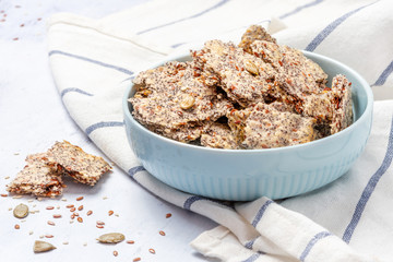 Homemade crackers with flax, sesame and poppy seeds in a bowl on a light background. Healthy food, tasty vegetarian and vegan snack. Crispy flat bread with seeds, superfood.