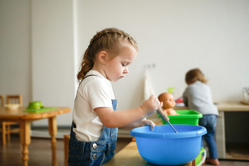 Toddler whips soap suds in basin at Montessori