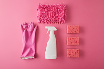 flat lay with spray bottle, sponges, rag and rubber gloves for house cleaning on pink