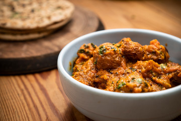 Potato curry (Kashmiri dum aloo) with chapatti (roti) served on wooden dining table.
