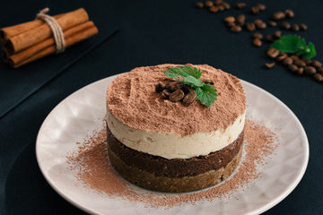 Tiramisu on a beige plate. Coffee with cinnamon. Raw dessert