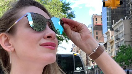 Female tourist in sunglasses looking at Flatiron Building in New York.