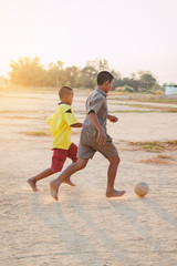 Action sport outdoors of kids having fun playing soccer football for exercise in community rural area under the twilight sunset sky. Fresh and vibrant image.