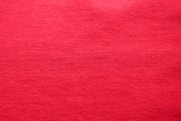 Red texture background of cotton fabric detail. Vibrant pink or cherry red colour cloth, empty natural material backdrop of casual plain burgundy color shirt  