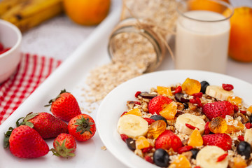 Close-up, Table top image of healthy homemade oats breakfast with soy milk and various fruit toppings in white plate on dining table.