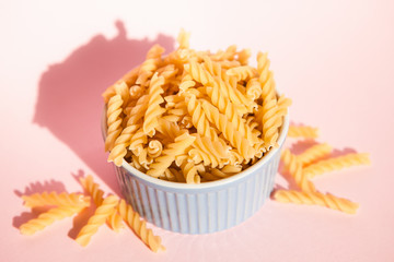 Italian rotini pasta in blue bowl on pink background