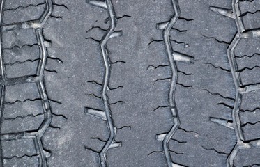 Old worn tread on a large truck tire showing the grooves and patterns up close. Road safety concept. Vehicle maintenance, problems detected.