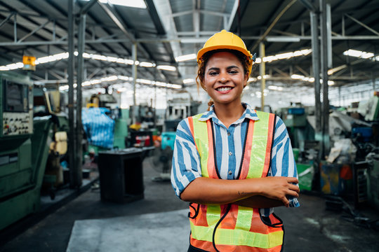 attractive young african woman smiling and working engineering in industry.Portrait of young female worker in the factory.Work at the Heavy Industry Manufacturing Facility concept.