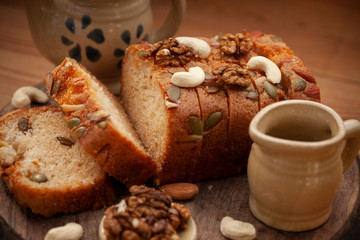 Close-up sweet bread cake loaf sliced garnished with walnut, Cashew, almond and sesame seeds tea kettle placed on the table.