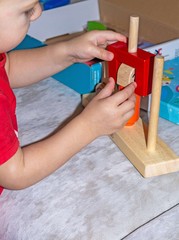 a child plays with educational wooden toys with colored details