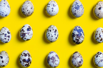Quail eggs on yellow paper, food design background. Top view