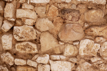 Yellow stone wall on a building as a background. The natural texture of the breed. Vintage facade, front view closeup