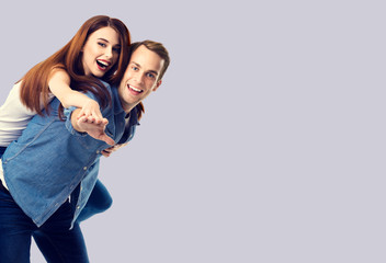 Love, relationship, dating, lovers, romantic concept - happy excited couple, in piggyback pose, against grey background. Copy space for some text.